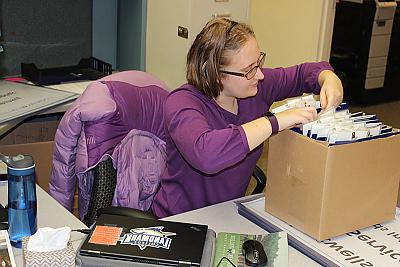 Landmark College student filing papers in office environment. 